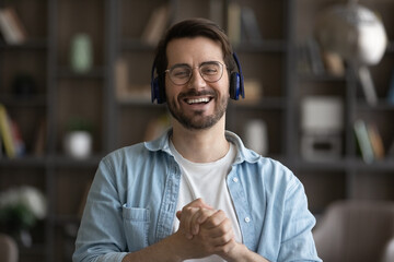 Head shot portrait laughing man in headphones and glasses looking at camera, excited young male...