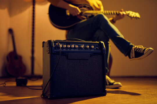Male musician playing acoustic guitar on the amplifier in retro vintage room. - Powered by Adobe