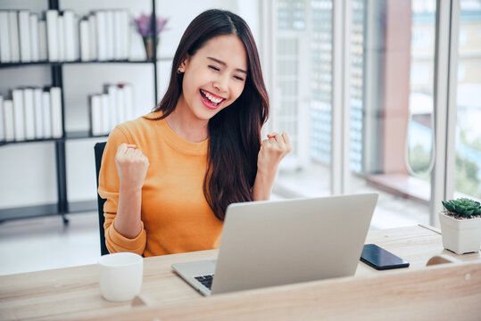 Happy Surprised Young Woman Is Working With A Laptop At Home Sitting On A Sofa, Asian Female Looks Excited After Receiving Letter With Good News.