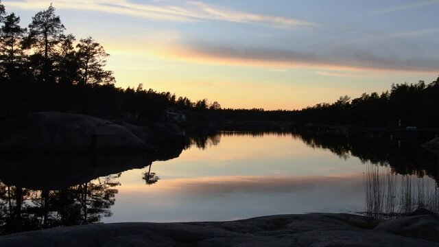 Sunset view of the Swedish archipelago and nature. Calm water with the sky reflecting in the water. Footage made outside Oskarshamn, Sweden
