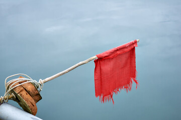 Broken red flag on a boat with calm sea