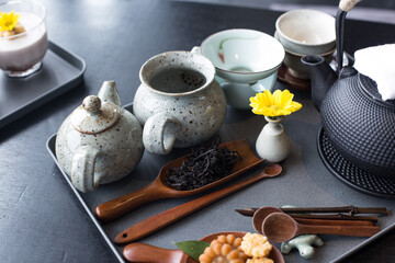 Asian food background with a tea set, cups, tea leaves, and teapot.