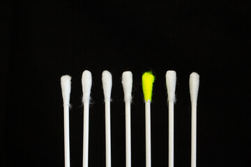 dare to be differant seven new white cotton buds isolated on a black background and one yellow