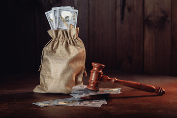 Money bag with dollar banknotes and judge's gavel. Litigation, dispute resolution, conflict of interest settlement