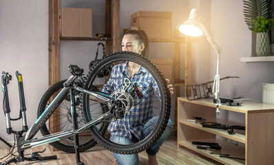 Woman fixing a mountain bike in a workshop. Concept of preparation for the new season, repair and maintenance