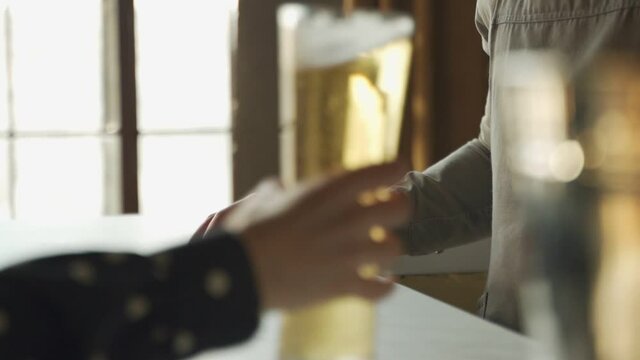 Slow motion bartender passes the drink to the customer across the table. Woman catches it. 