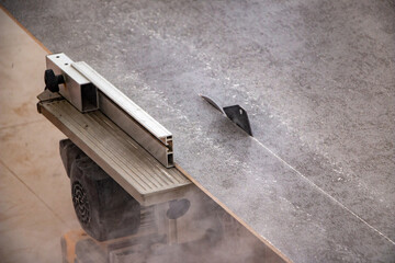 male hands of  construction worker sawing and cutting parts of  electric miter saw from  wooden board. wood board cutting process with blade rotation and dusty cloud electric miter saw