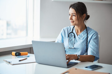 Charming female doctor using laptop in clinic