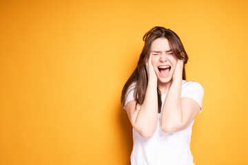Angry girl in a white t-shirt screams with pain in her teeth due to the installation of braces