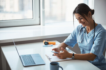 Cheerful female doctor using mobile phone in clinic