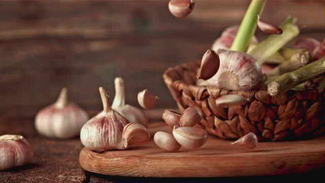 Super slow motion garlic falls on a wooden background. Filmed on a high-speed camera, 1000 fps. High quality FullHD footage