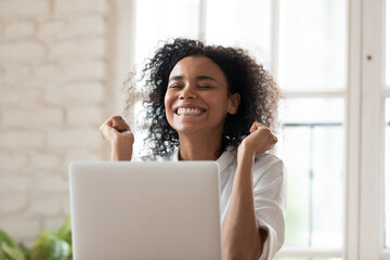 Overjoyed smiling young african ethnicity female employee feeling excited of reading email on...