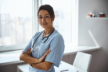 Charming female doctor standing in her office in clinic