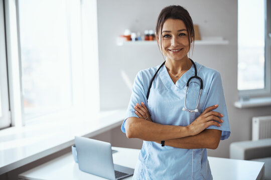 Joyful female doctor standing in her office in clinic