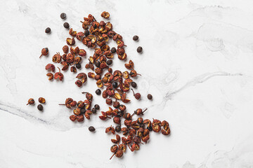 Sichuan pepper on white marble background.