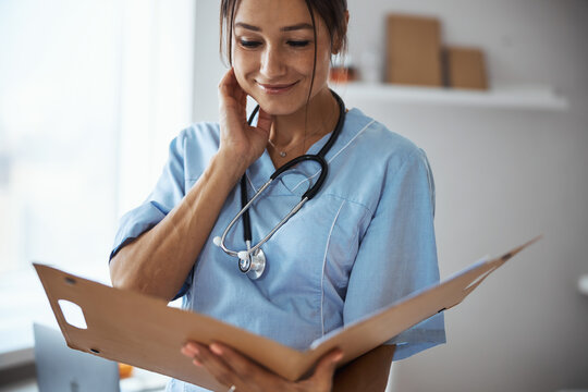 Nice female doctor studying documents in clinic