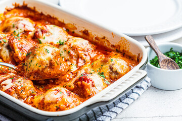 Closeup of baked cheesy meatballs casserole with tomato sauce in the oven dish.