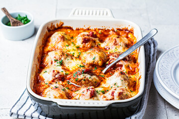 Baked cheese meatballs casserole with tomato sauce in the oven dish.