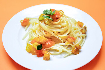 plate of noodles with vegetables on an orange and yellow background. selective focus. copy space