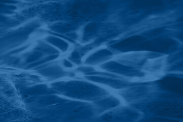 Trendy blue colored low contrast abstract background with light and shadows caustic effect. Light passes through a glass. Water background. 
