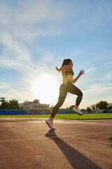 Young sport woman running at a track and field stadium