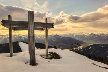 beautiful sunrise on the mountains with a panoramic view of the alps and a wood cross in the foreground