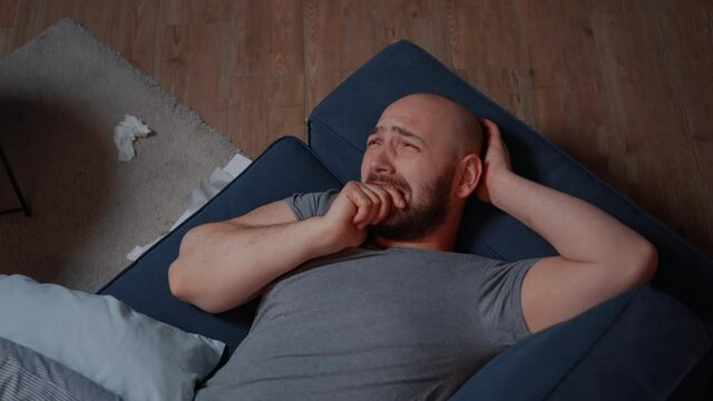 Alone depressed traumatized stressed man with mental health issues feeling anxiety and sadness increase while crying desperately thinking at his miserable life. Male suffering from chronic disease