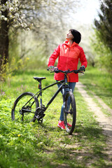 Beautiful woman on a bike in a blooming spring garden. Beautiful mature woman posing for the camera in a blooming spring garden. 