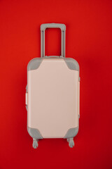 Pink suitcase on wheels on a red background. Travel concept. Vertical image