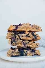 Stack of freshly baked oat blueberry scones on white plate, close up. Sweet food with natural ingredients. Vegan gluten free pastry.
