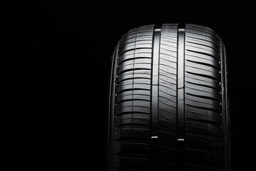 modern summer tire with two drainage channels on a black background, front view, copy space
