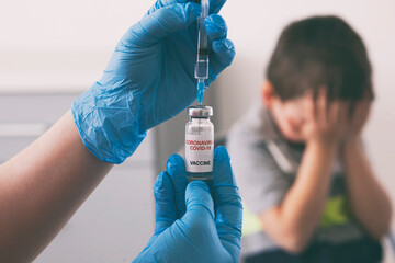 The child fears the injection. Boy covered his face with his hands because scared of vaccination