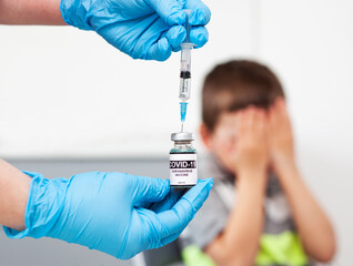 The child fears the injection. Boy covered his face with his hands because scared of vaccination