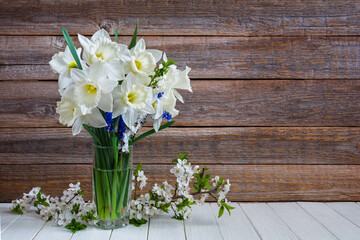Bouquet of beautiful daffodil flowers in a vase on a wooden table. Still life