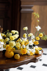 A delicate composition with yellow flowers and fruits, with wedding invitations. Wedding decor in trendy shades, composition on the table with printing.