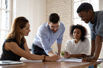 Happy millennial multiracial business people discussing project development strategy, analyzing...
