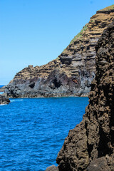 Grandes montañas de rocas en las costas del mar con un cielo azul y nubes blancas 
