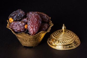 Islamic fasting festival and holy month of Ramadan concept: A golden metallic ornate bowl and cap...