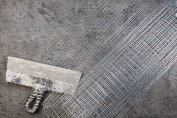 roll mesh for plastering, putty knife on the gray concrete background. Copy space. Top view.
