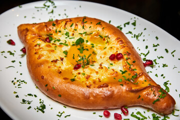 Ajarian traditional flatbread khachapuri or hachapuri with cheese, egg and butter on a plate