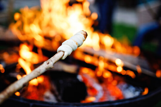 Stick bread twisted on skewer or stick, roasted on flame of fire. Popular party and camp barbecue food in Germany called Stockbrot. Fun for children. Healthy snack