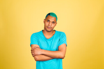 Black african man in casual on yellow background look to camera thoughtful with smile crossed hands arms