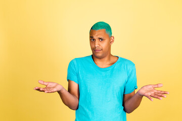 Black african man in casual on yellow background look to camera shrugging shoulders clueless and...