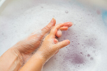 Women's and children's hands in white foam. Hygiene and cleanliness, skin care. High quality photo