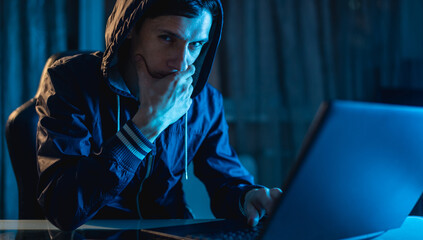 Male in the hood looking in the camera. Hacker attacks and stealing access databases with...