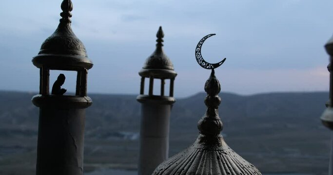 Silhouette of mosque building on sunset. Ramadan Kareem background. Realistic mosque miniature with prayer silhouette. Selective focus