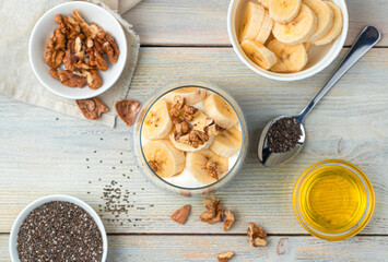 Banana cream pudding with chia seeds and nuts on a beige background. Top view.