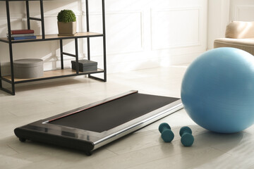 Modern walking treadmill, dumbbells and fitness ball in living room. Home gym equipment © New Africa