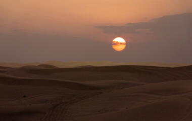 Desert sunset with sun disk over sand dunes, United Arab Emirates, Dubai