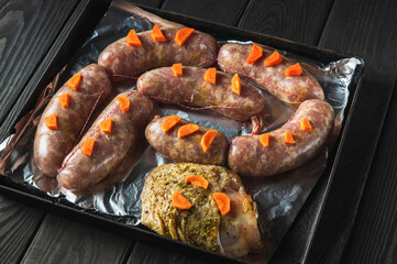 Raw meat sausage with carrots and ham on a Sheet pan is prepared for baking in the oven. The national meat dish is prepared before the holidays